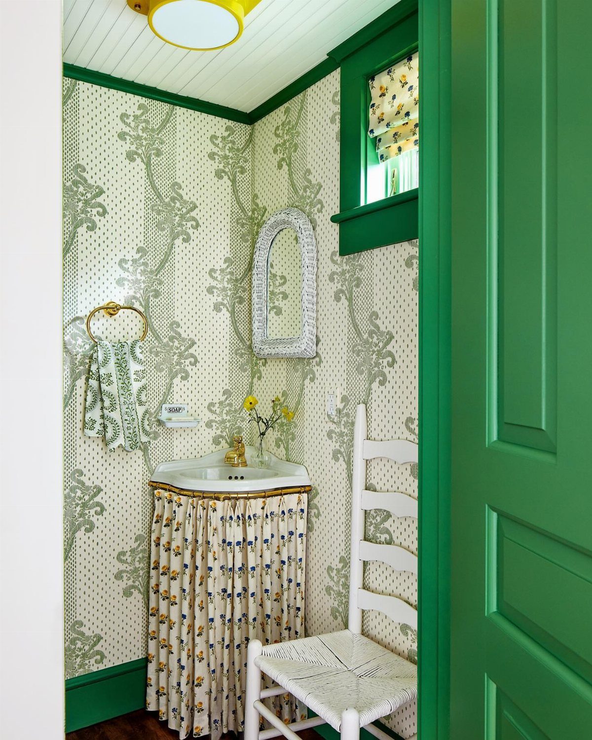 A pedestal sink featuring a decorative floral fabric skirt in a patterned bathroom.